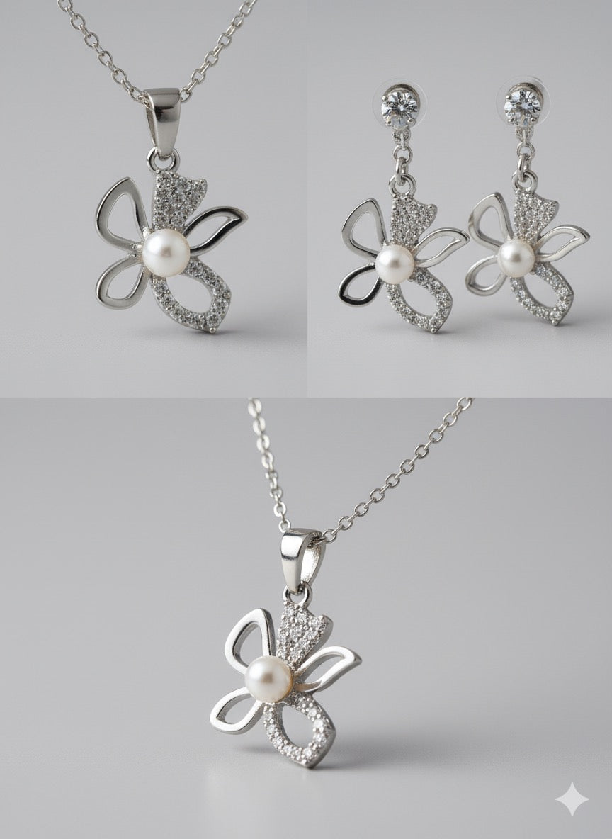 Butterfly-shaped silver jewelry set with pearls on a gray background