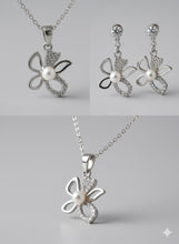 Butterfly-shaped silver jewelry set with pearls on a gray background